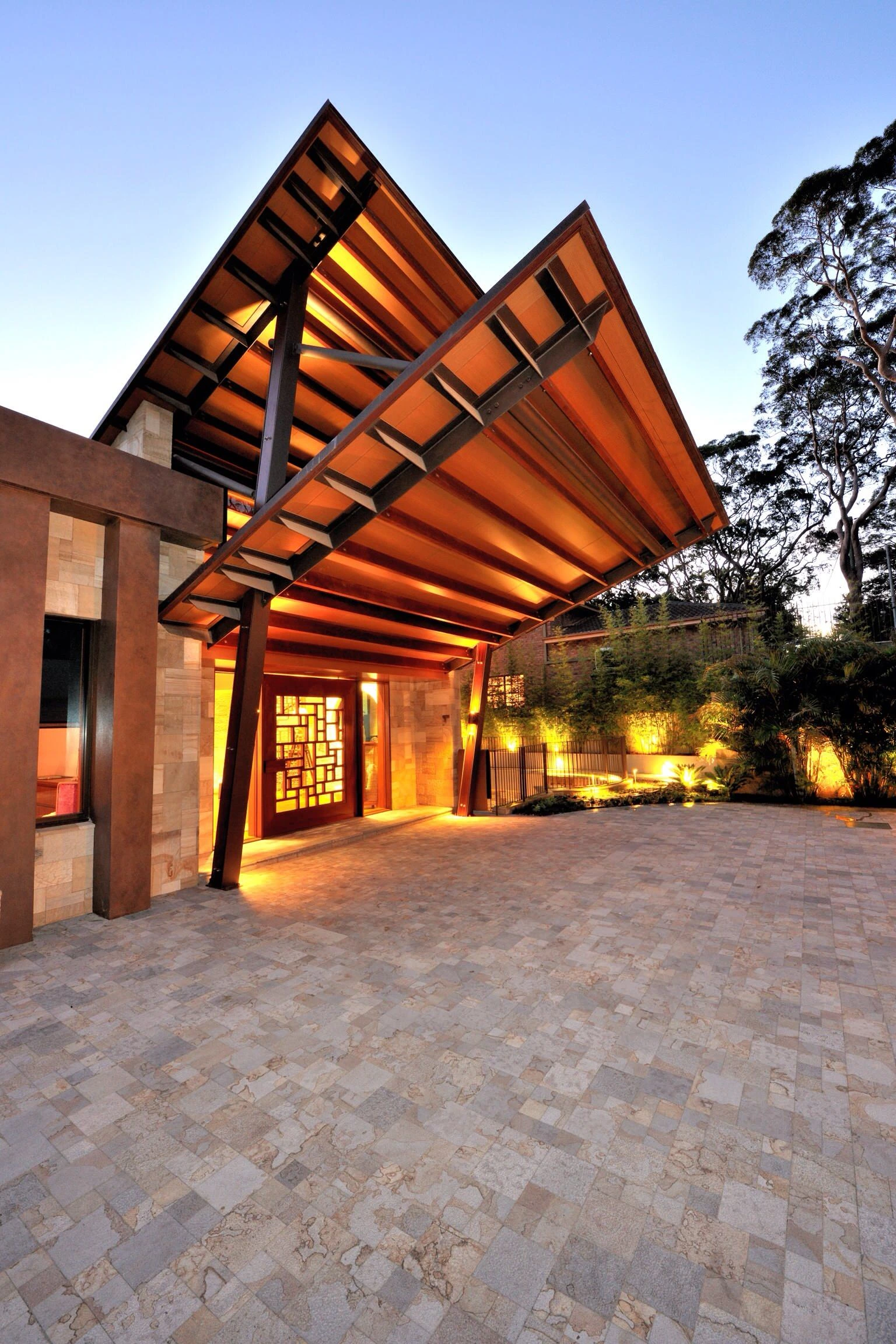 Custom concrete driveway in Lewisville TX with detailed paver patterns, leading to an elegant covered entryway with dramatic evening lighting and architectural details.